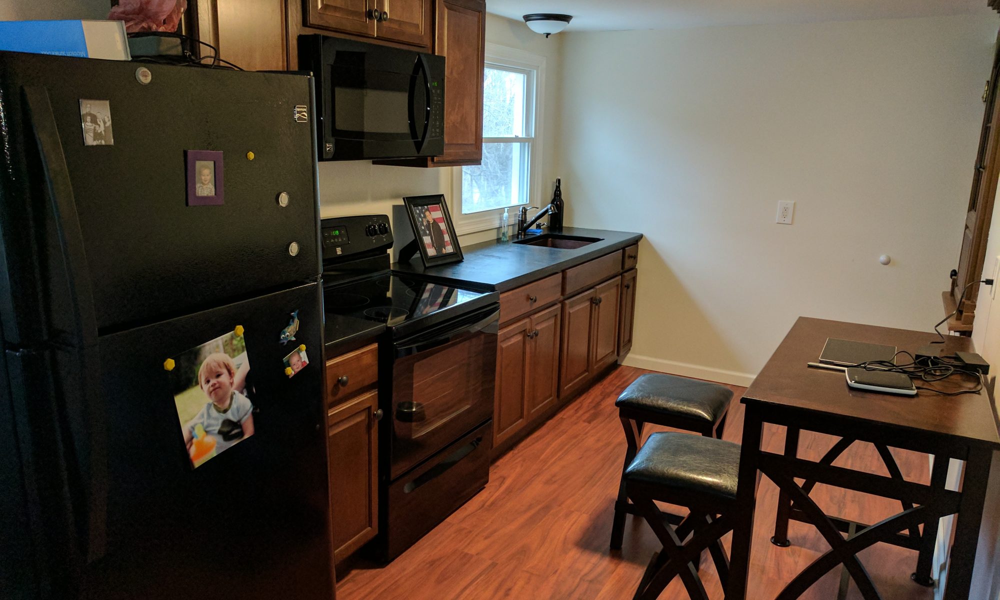 A galley kitchen with breakfast area and darker wood cabinets