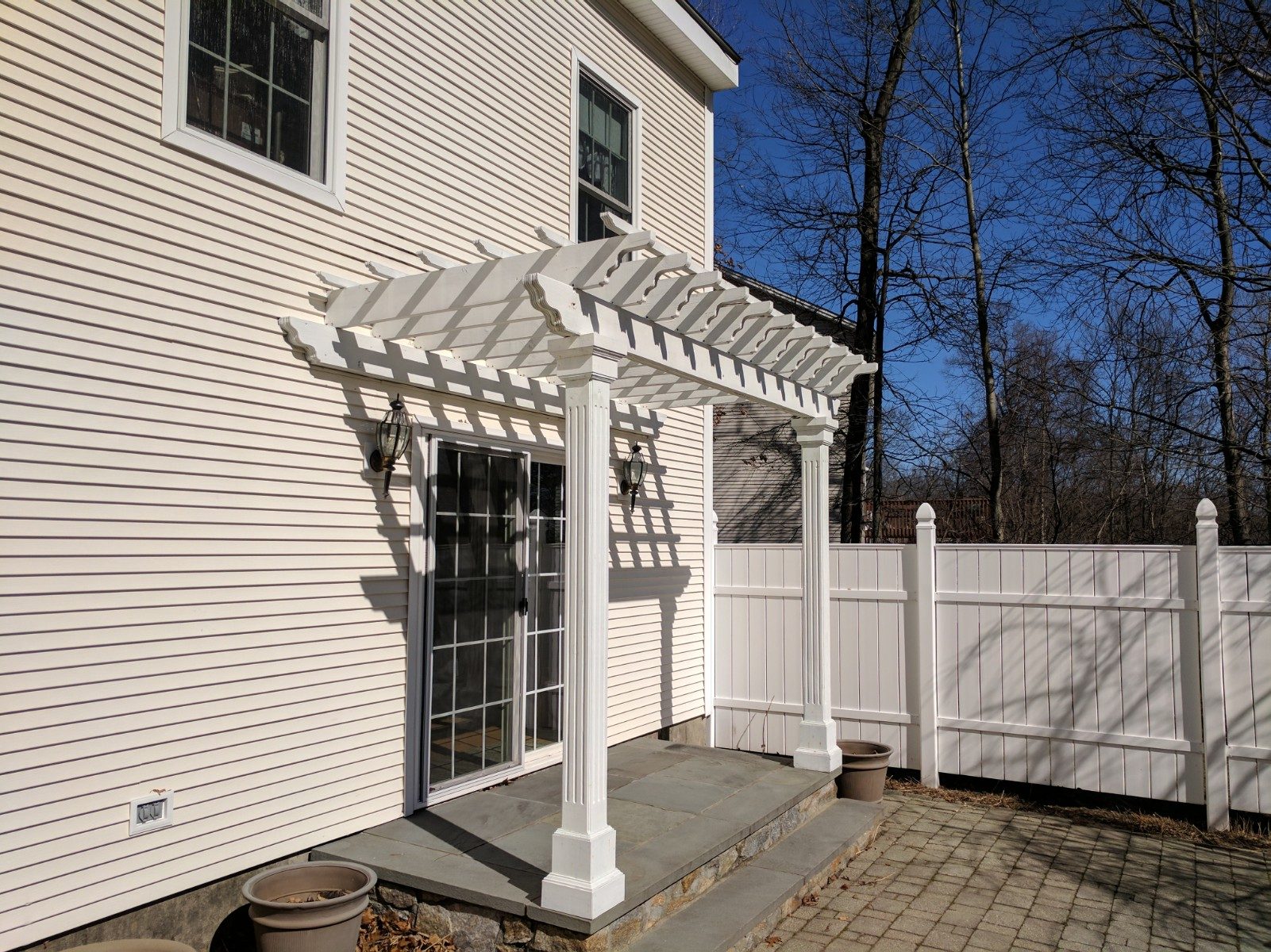 A pergola above a sliding glass door leading to a patio